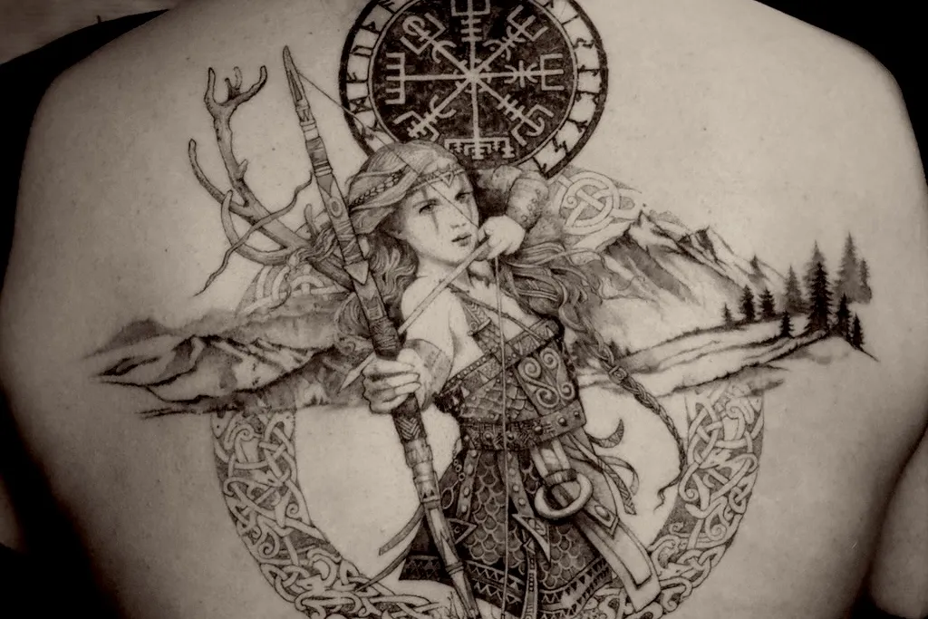 Tatouage détaillé d'une déesse avec plumes de paon et halo lunaire réalisé par Épure Atelier