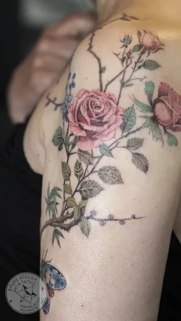 Tatouage roses réalistes avec feuillage et branches sur l'épaule